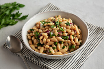 Homemade White Bean Salad with Herbs and Onion in a Bowl, side view.