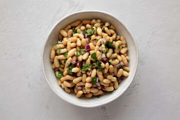 Homemade White Bean Salad with Herbs and Onion in a Bowl, top view. Flat lay, overhead, from above.