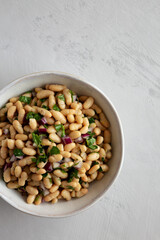 Homemade White Bean Salad with Herbs and Onion in a Bowl, top view. Flat lay, overhead, from above.