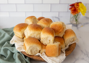 Freshly Baked Dinner Rolls in a Wooden Bowl on a White Countertop with White Tile Background