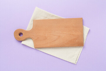 Cutting board with napkin on color background, top view