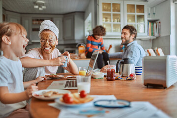 Happy family enjoying breakfast together in modern kitchen with laptop