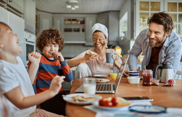 Happy family enjoying breakfast together in modern kitchen with laptop