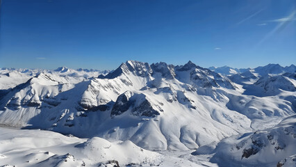 Obraz premium A panoramic view of a snowy mountain range under a clear blue sky