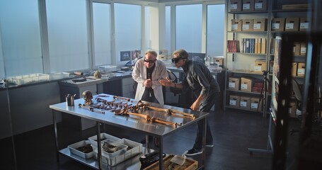 Two archaeologists conduct historical and scientific research in archaeological laboratory using...