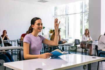 Female student raising her hand in class to ask some question.