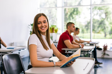 Portrait of female student reading a book in class.