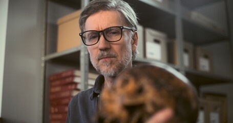 Two archaeologists analyze and examine skull of ancient extinct human, have discussion during...