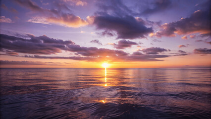 Fototapeta premium A beautiful sunset over a calm ocean with the sun dipping below the Horizon