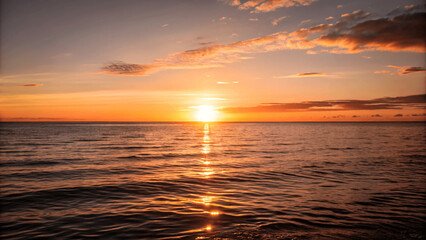Obraz premium A beautiful sunset over a calm ocean with the sun dipping below the Horizon