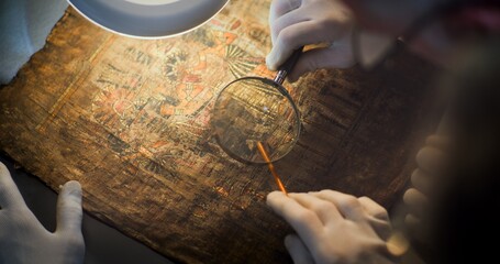 Two scientists examine ancient Egyptian papyrus together in archaeological lab. Team of...