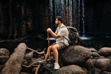 Man resting in front of a waterfall