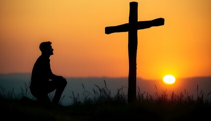 Silhouette of man kneeling near the wooden Christian cross on a nature meadow grass field outdoor at sunset