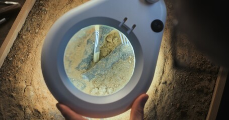 Close up of paleoanthropologist or archaeologist cleaning bone of ancient prehistoric human with...