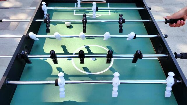 Close-up of a table football game. Friends have fun playing board football together. City park.	