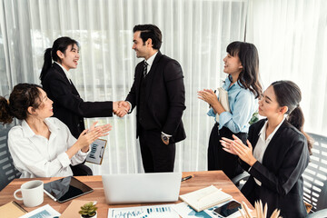 Group of businesspeople shake hand after made successful business agreement meeting. Diverse race office worker celebrate after made progress on marketing planning in corporate office. Meticulous