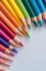 Fototapeta premium Colorful arranged colored pencils on a white surface in a creative workspace