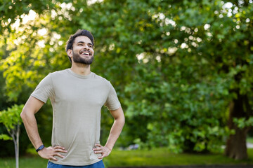 Joyful man enjoying outdoor fitness in lush park setting wearing casual clothing and smiling...