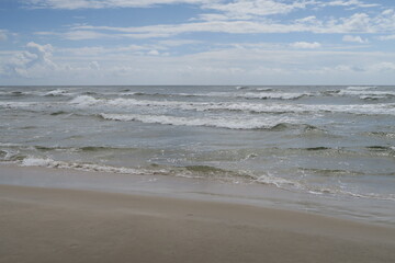 Wellen brechen am Strand von Sandhammaren in Ystad an einem sonnigen Sommertag.