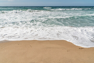 In Sardegna una spiaggia con la sabbia gialla e onde alte in estate.