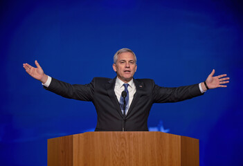 A gray-haired politician with both hands raised