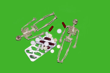 Skeletons lying next to pills and capsules. Danger of drug overdose, medication use, pills. Health risk from uncontrolled drug use.