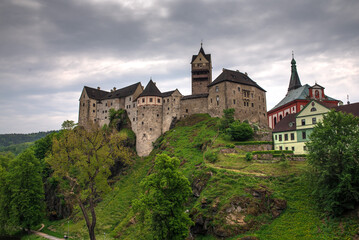Obraz premium Medieval Loket Castle in the Czech Republic in summer under a cloudy sky.