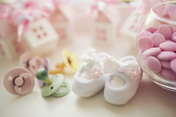 Baby shoe, pacifiers, pink boxes and cross for Christening. Girl baby birthday party or baby shower