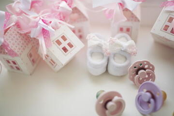 Baby shoe, pacifiers, pink boxes and cross for Christening. Girl baby birthday party or baby shower