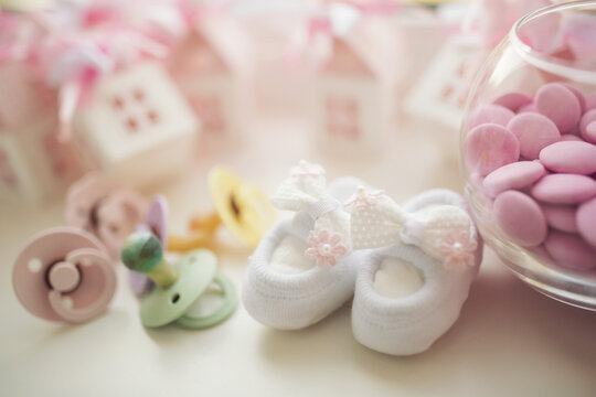 Baby shoe, pacifiers, pink boxes and cross for Christening. Girl baby birthday party or baby shower