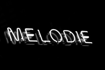 Isolated white neon sign 'melodie' on black background