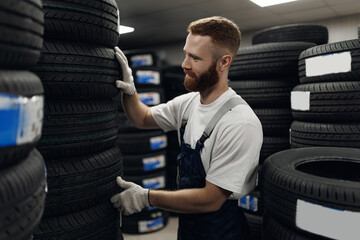 Specialist man tire fitting in car fix service. Mechanic checks tyre and rubber tread for safety © Parilov