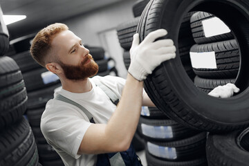 Portrait happy man mechanic hands hold black tire in tyre store or workshop auto fix service © Parilov