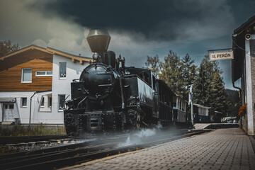 Historic steam locomotive in train station. Steam locomotive pump out clouds of smoke. Steam train with white smoke. Steam train on railway. Vintage steam train ride.