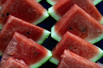 juicy watermelon on a blue plate, the watermelon is cut in triangles, the sun hits the watermelon