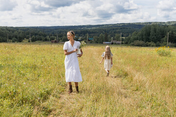 mother and daughter walking along a path in a grassy meadow, they are carefree, summer