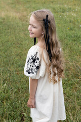 Five year old girl wearing white dress and standing on grass