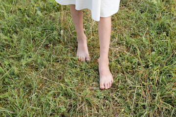 Girl walking barefoot on green grass, closeup