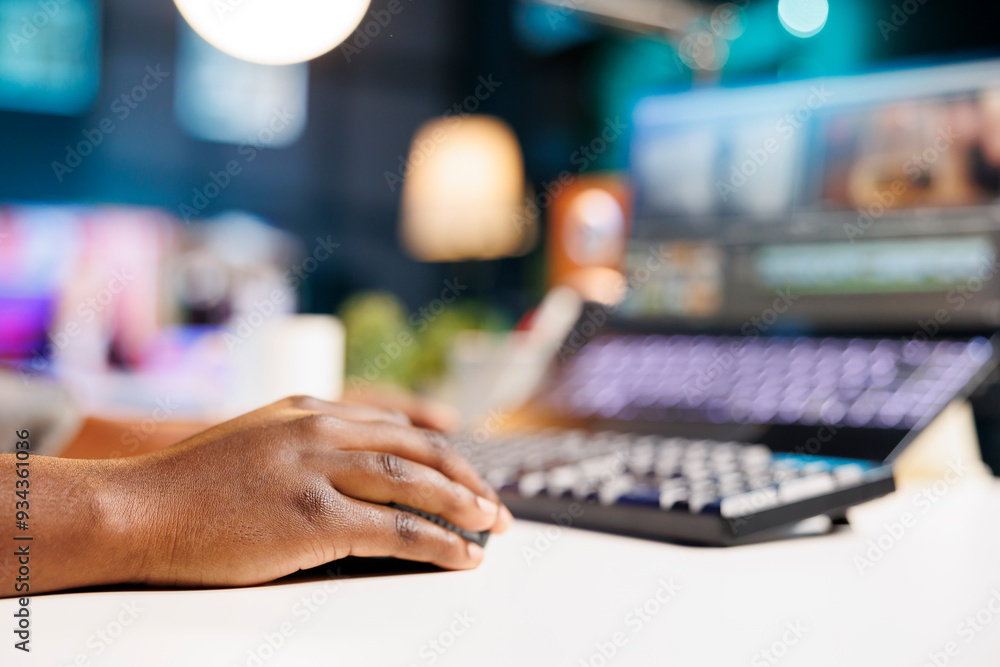 Aufkleber close-up of african american hand holding digital mouse browsing on her laptop. detailed view of a b