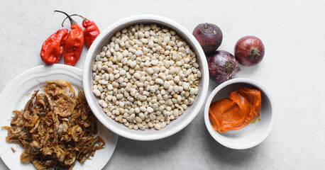 Overhead view of ingredients for making nigerian stewed beans on a granite countertop, top view of mise en place of ingredients for making ewa riro, process of making nigerian ewa riro