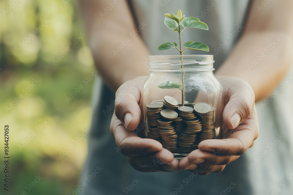 Wall mural hands holding a jar filled with coins and a growing plant, symbolizing financial growth and investme