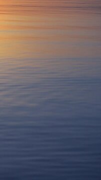 Vertical video of a reflect majestic sunset on a water surface.