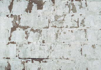 Light gray, almost white cinder block wall covered with lime chalk water-based paint. Old stone surface texture. Close-up.