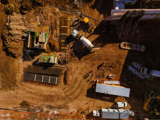 Top aerial view of a construction site with cement mixer truck, machinery and workers