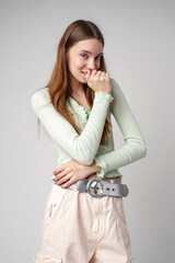 Young Woman With Long Brown Hair Smiles Shyly While Covering Her Mouth With Her Hand