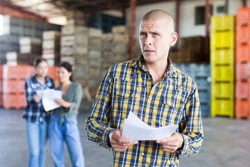 Obraz premium Confident male manager with documents inside a large warehouse