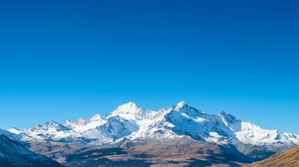 Majestic mountain range with snow-capped peaks and clear blue sky above. Majestic Mountain Range