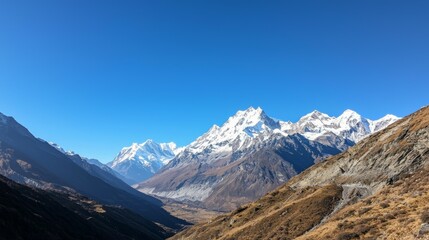 Fototapeta premium Majestic mountain range with snow-capped peaks and clear blue sky above. Majestic Mountain Range