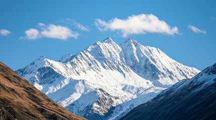 Obraz premium Majestic mountain range with snow-capped peaks and clear blue sky above. Majestic Mountain Range