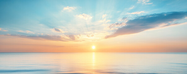 Obraz premium The sun is setting over the ocean, casting a warm glow on the water. The sky is filled with clouds, creating a serene and peaceful atmosphere
